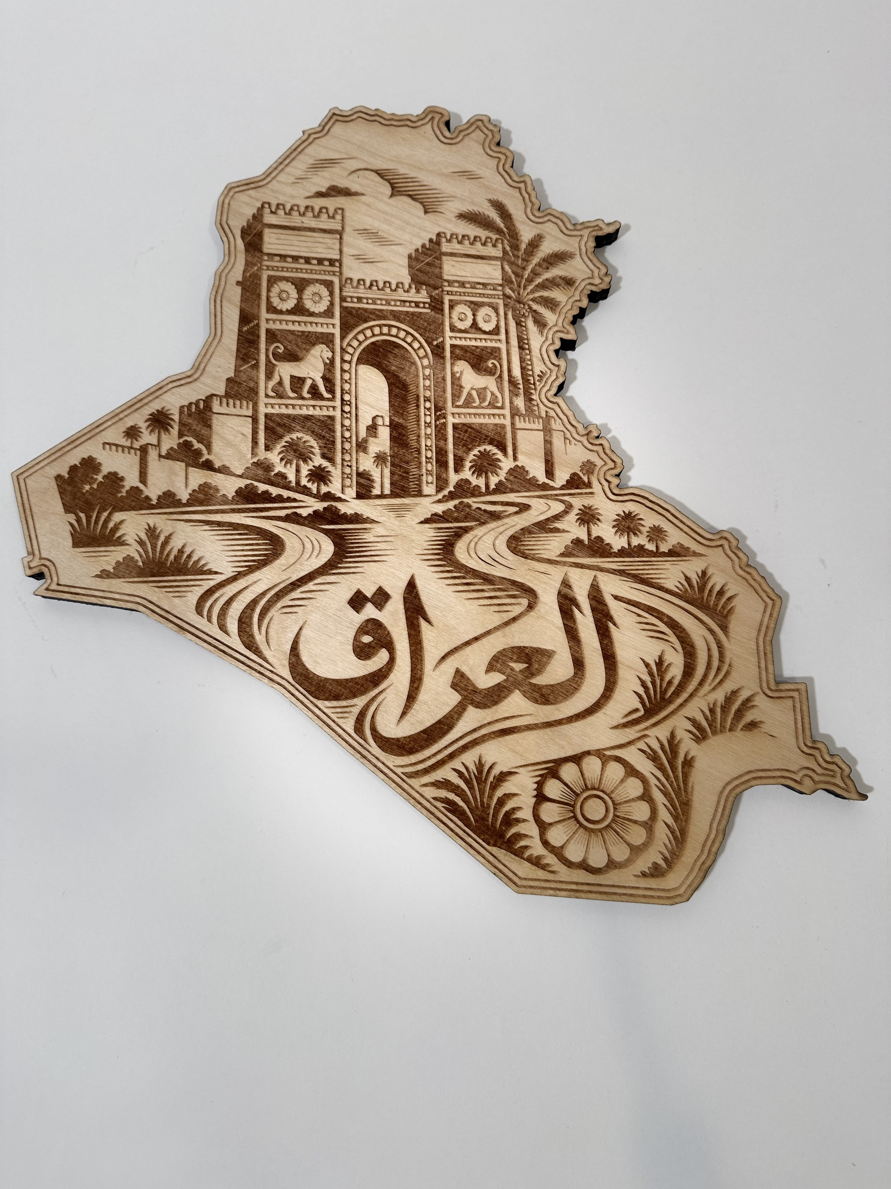 Real product photograph of Iraq wood wall art, showing a twin-towered gateway, lions, two rivers, palms, a rosette and العراق and natural wood grain.