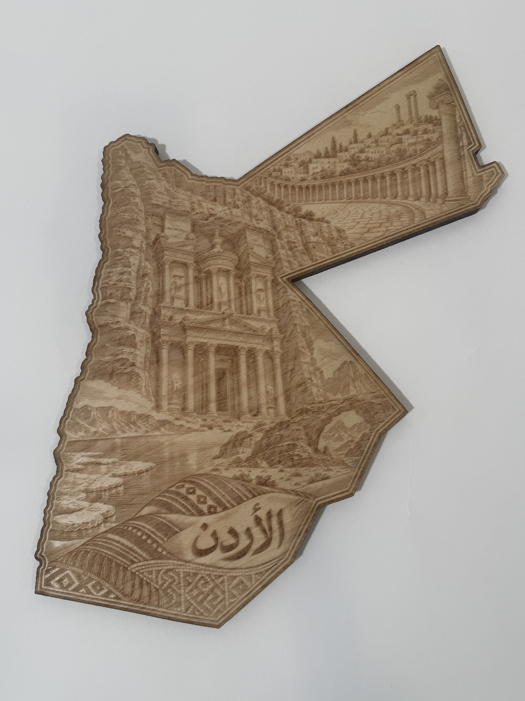Real product photograph of Jordan wood wall art, showing a rock-cut façade, colonnaded plaza, rock arch, water and الأردن and natural wood grain.