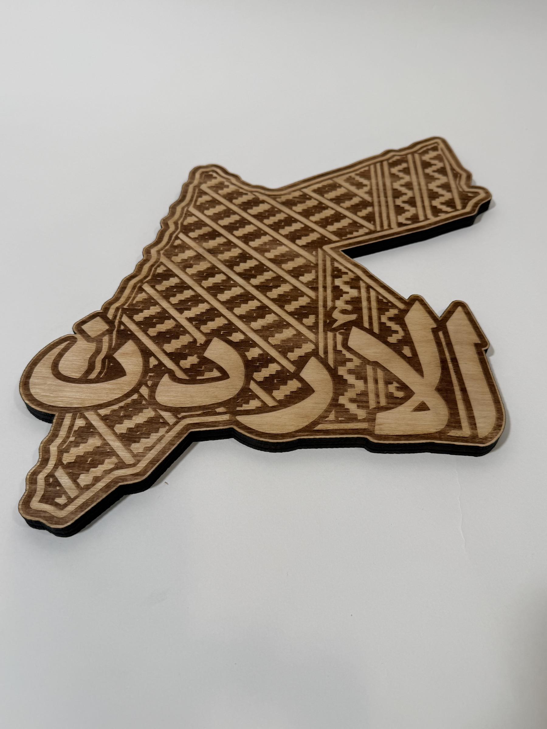 Real product photograph of Jordan wood wall art, showing stepped woven-style patterns, a double border and large الأردن calligraphy and natural wood grain.