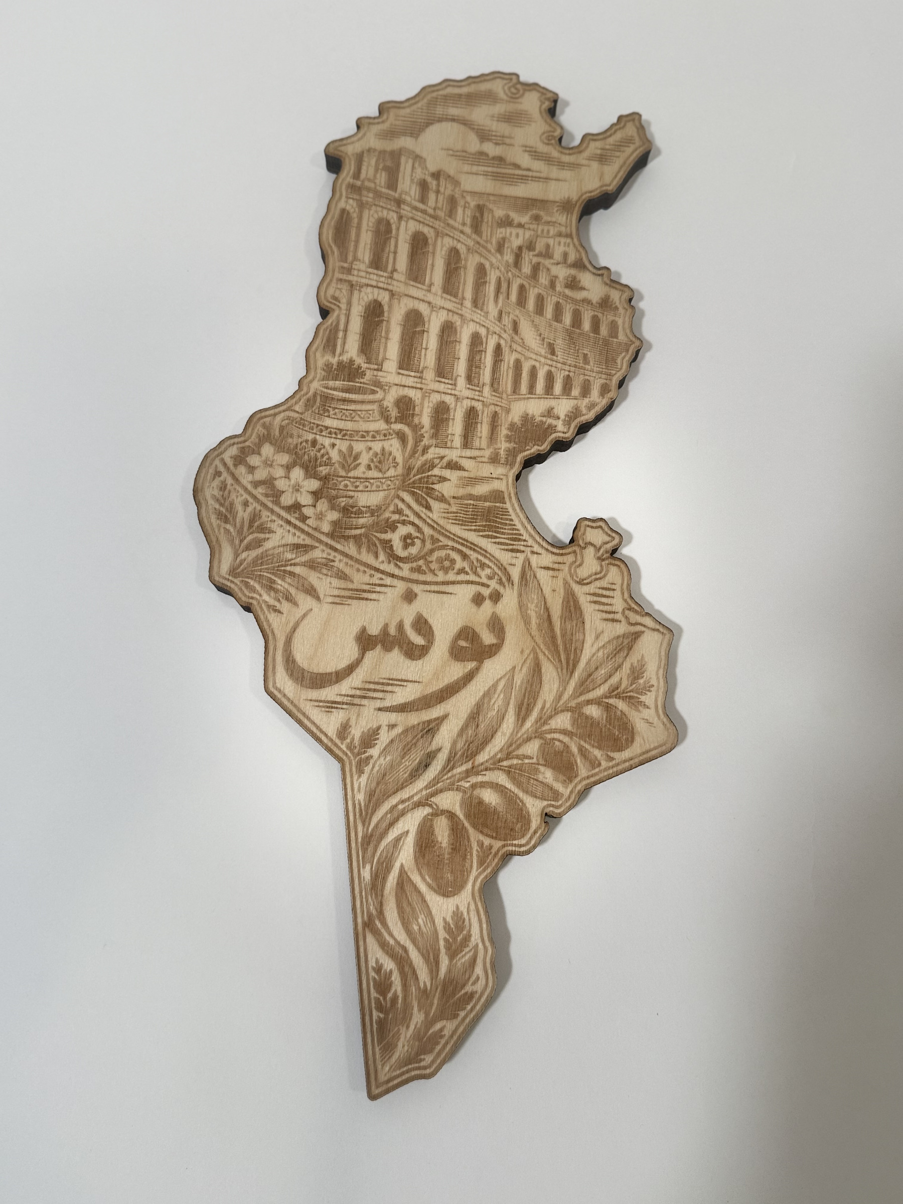 Real product photograph of Tunisia wood wall art, showing an amphitheater, patterned pottery, flowers, olive branches and تونس and natural wood grain.